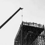 A dramatic black and white image of a construction crane and scaffold, highlighting industrial architecture.